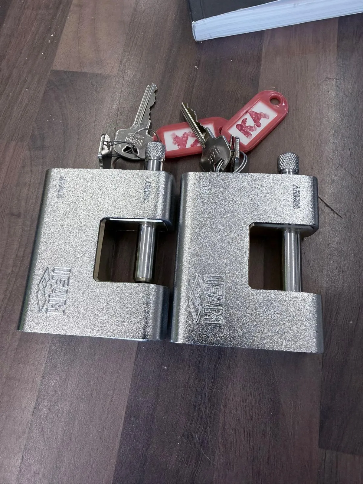 Two heavy-duty padlocks with their keys on red tags